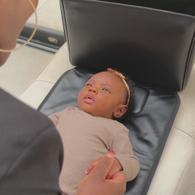 zen3 changing bag opened out into a built-in black memory foam changing bed with baby laying down calmly ready for a nappy change 